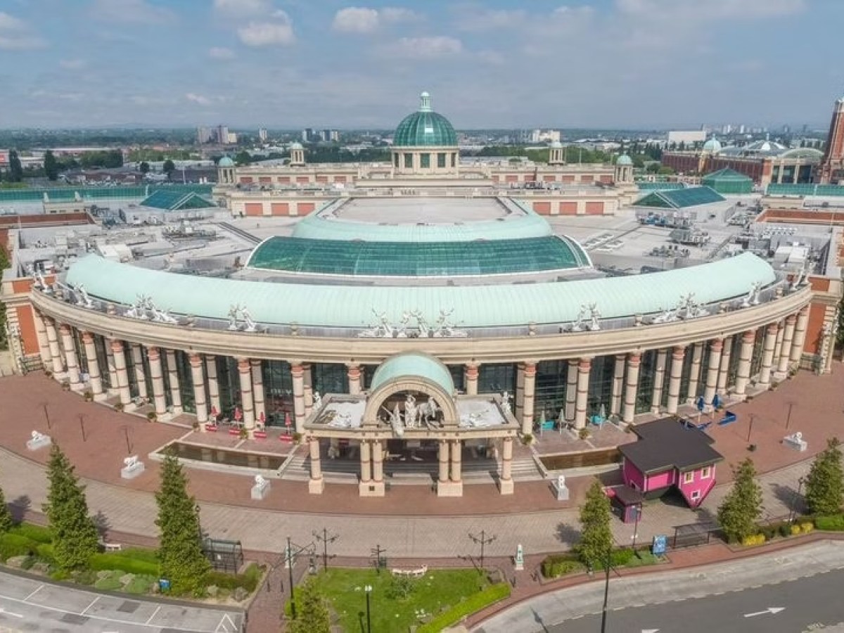 Aerial view of a large, circular classical-style building with a green dome and columns.