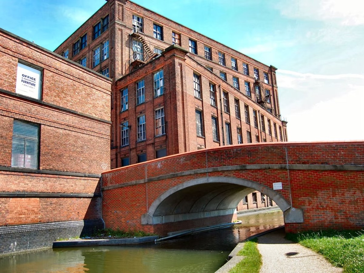 Brick building and bridge over a canal on a sunny day.