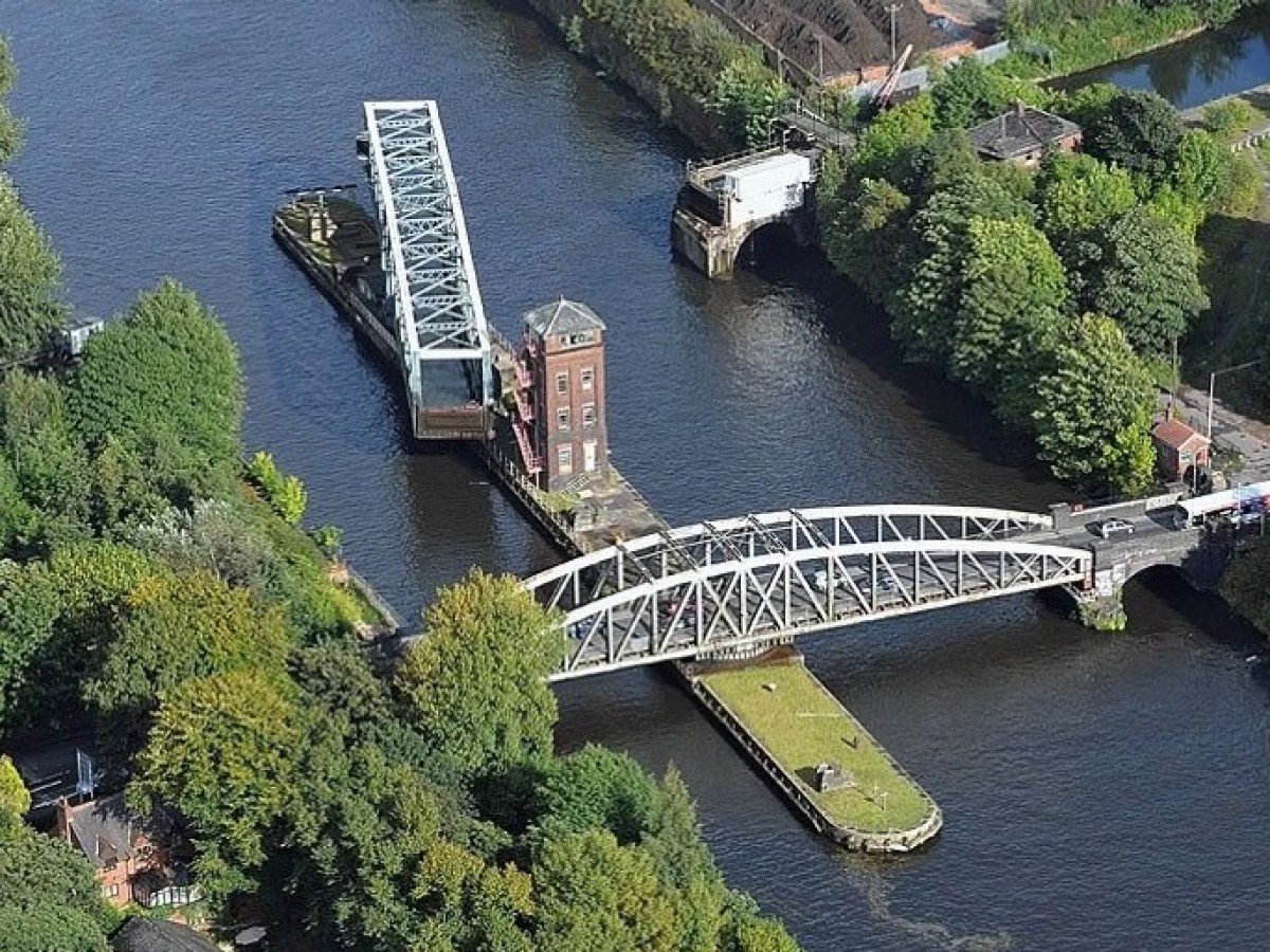 Aerial view of a swing bridge open over a river surrounded by trees.