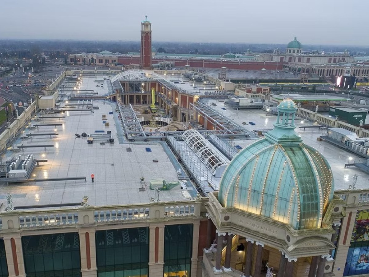 Aerial view of a large shopping mall with a glass dome and tower under a cloudy sky.