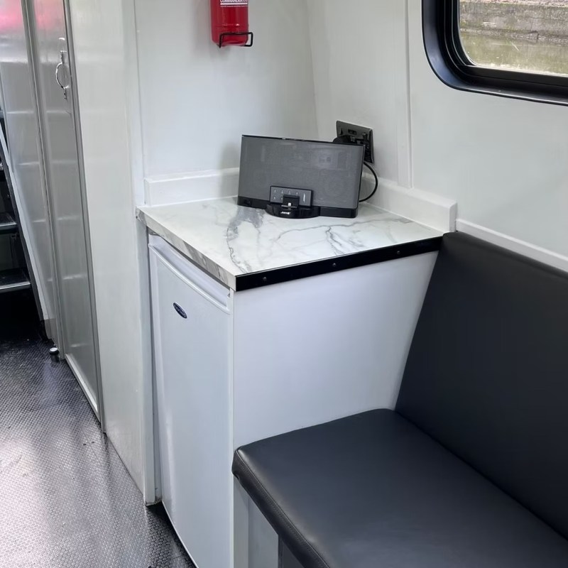 Interior with a small fridge, counter, bench seat, and stairs.