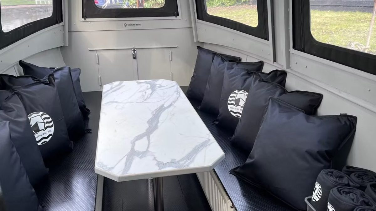 Boat cabin with marble table, black seats, and matching cushions.