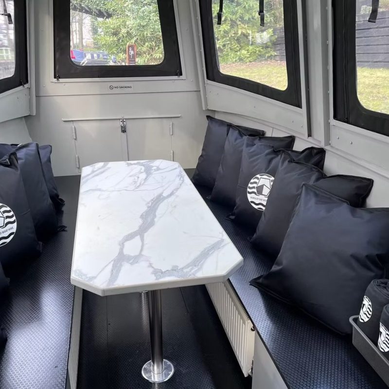 Boat cabin with marble table, black seats, and matching cushions.