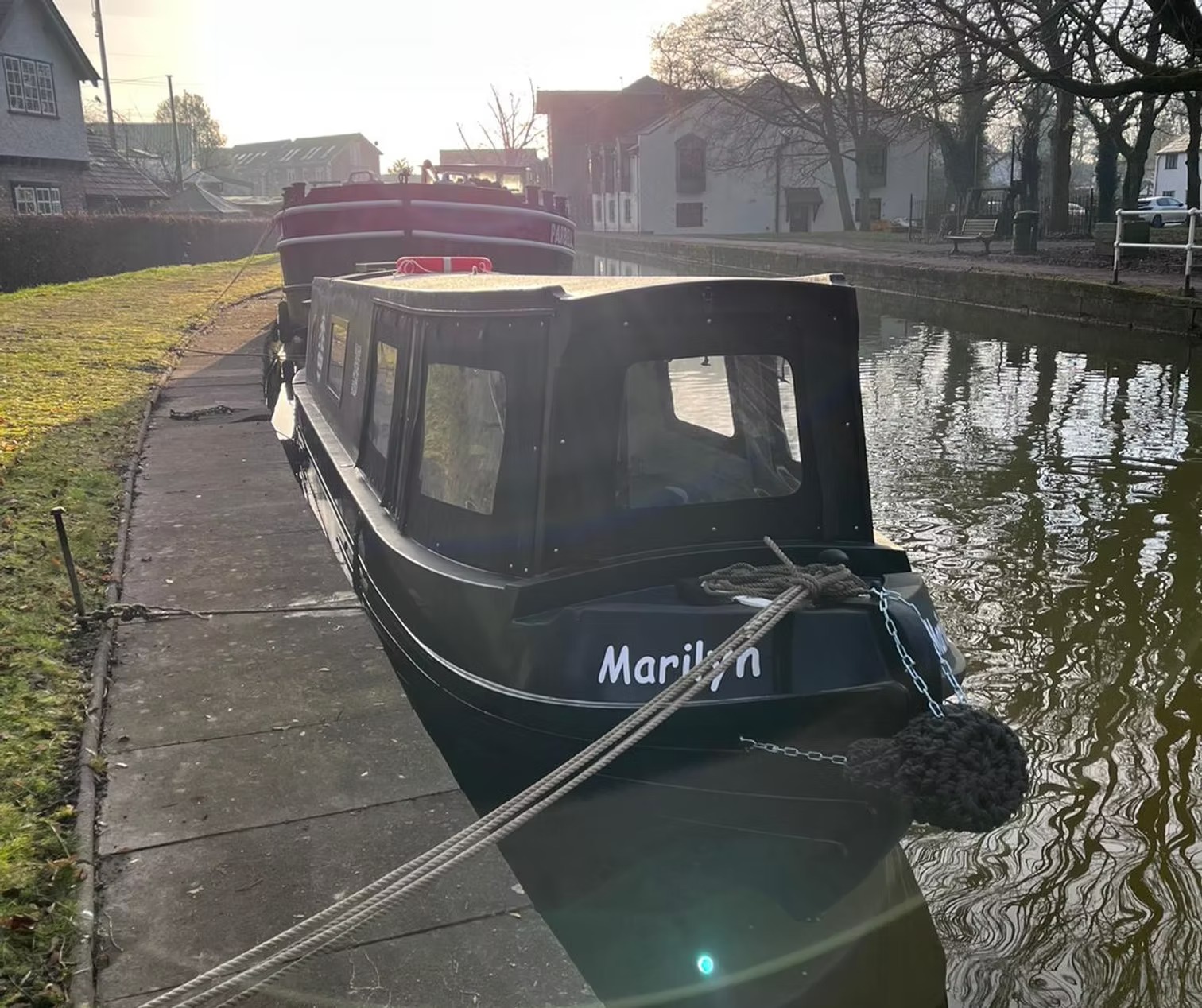 Narrowboat moored on a canal in early morning light.