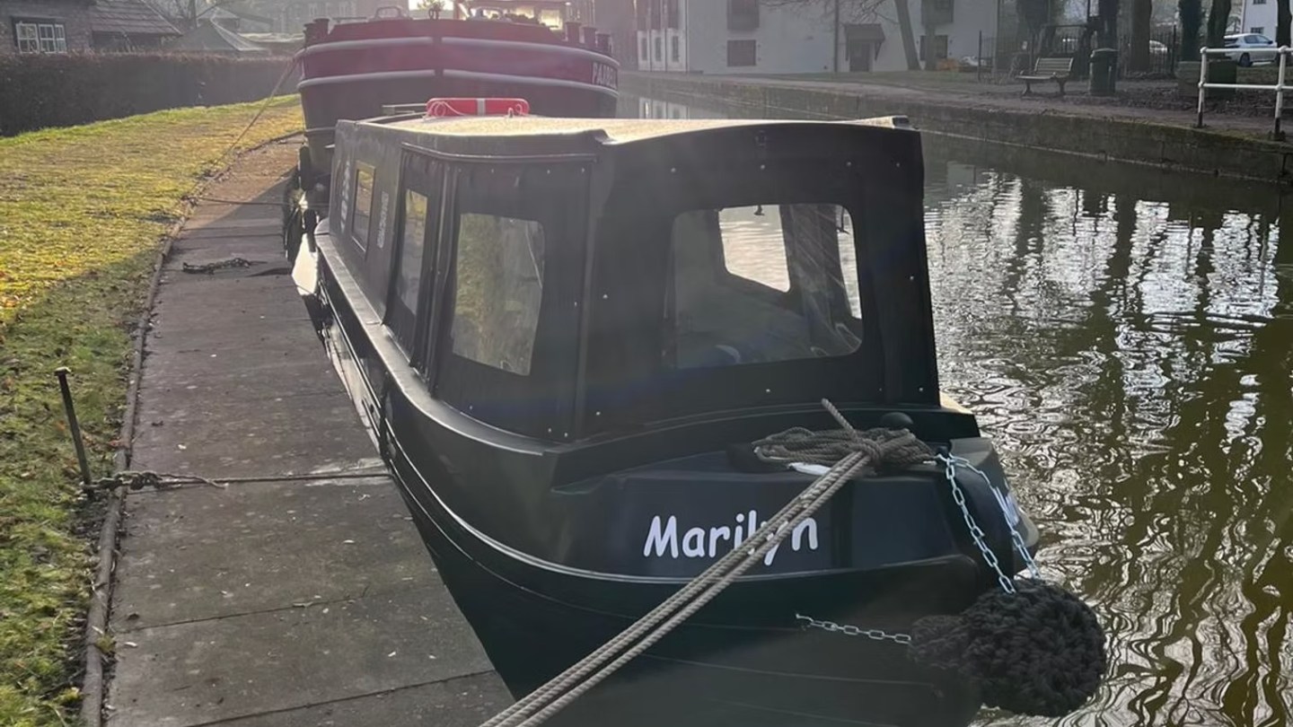 Canal boat named Marilyn moored by a grassy bank on a sunny day.