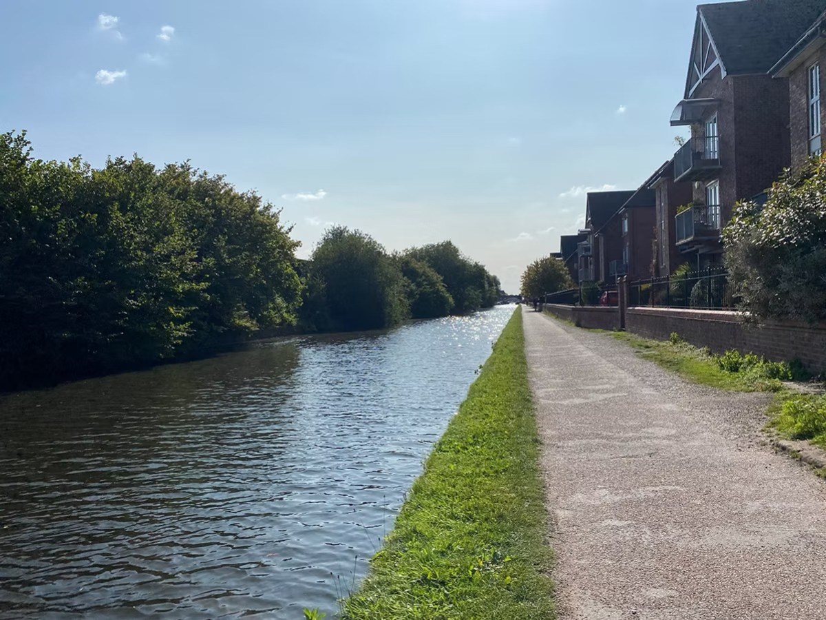 Canal lined with trees and houses under a clear blue sky.