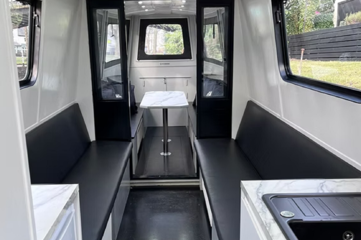 Interior of a modern boat with black seating and a central table.